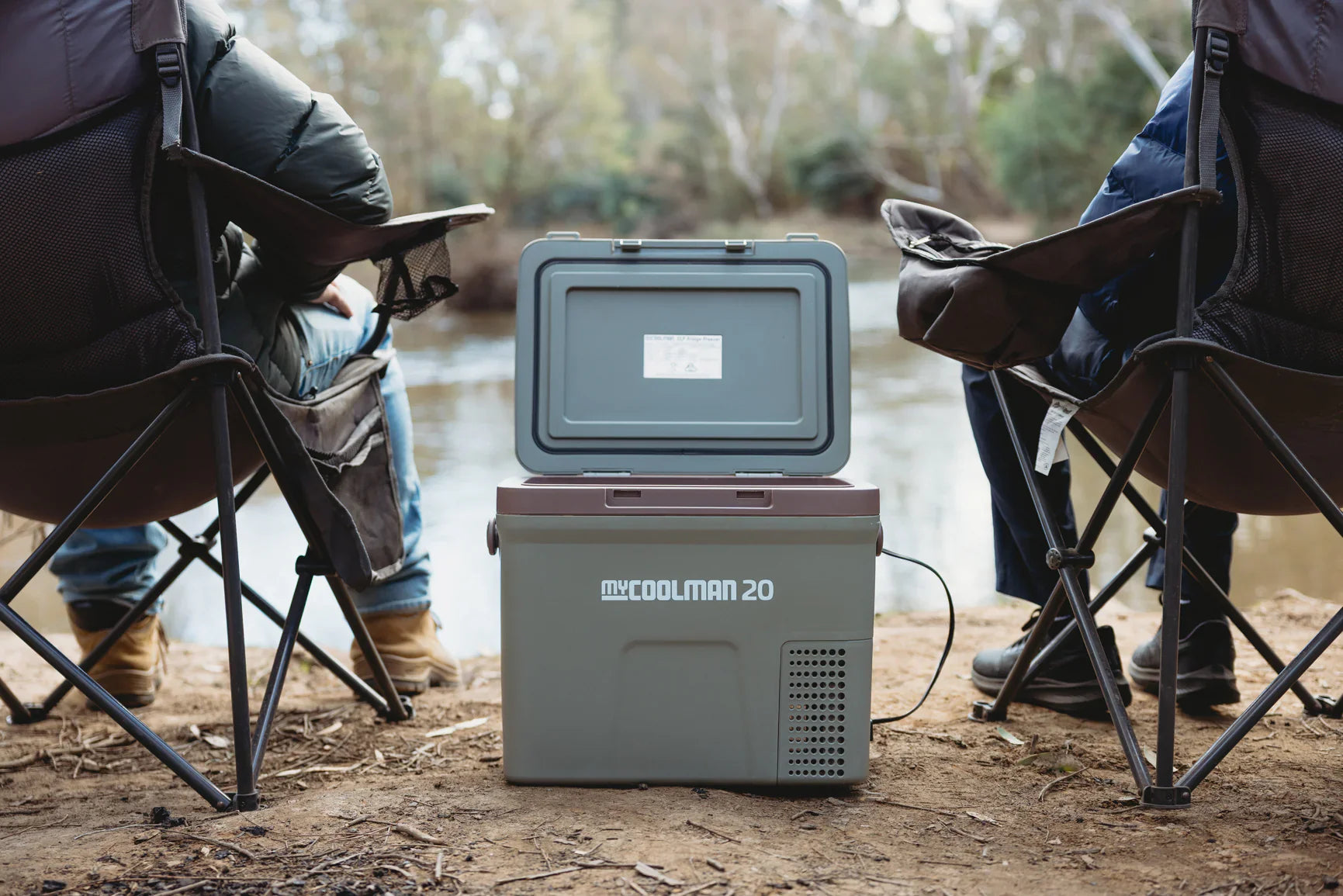 myCOOLMAN cooler placed between two camping chairs outdoors — lifestyle scene of the portable fridge in use – Top 7 myCOOLMAN Dual Zone Fridge / Freezers Every Caravan Owner Needs